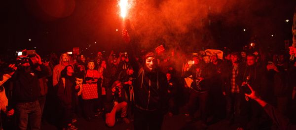 An anti-capitalist protester wearing aGuy Fawkes mask holds a lit flare during the Million Masks March, organised by the group Anonymous, near the Houses of Parliament in central London on November 5, 2015. - Sputnik International