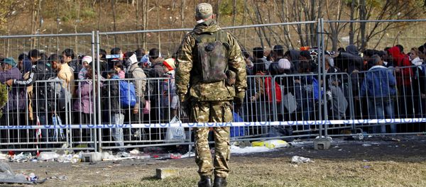 A Slovenian soldier observes migrants as they wait to cross the border into Spielfeld in Austria from the village of Sentilj, Slovenia, October 31, 2015 - Sputnik International