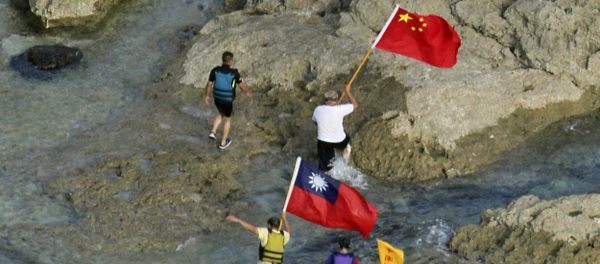 In a photograph taken on August 15, 2012, pro-China activists carrying Chinese and Taiwanese national flags walk on the disputed island known as Senkaku in Japan and Diaoyu in China after arriving on their boat, west of Japan's sourthern island of Okinawa - Sputnik International