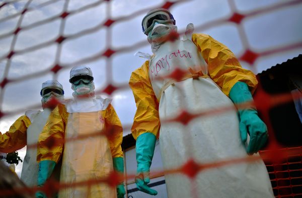 A file picture taken on August 14, 2014 shows Medecins Sans Frontieres (MSF) medical staff wearing protective clothing treating the body of an Ebola victim at their facility in Kailahun. - Sputnik International
