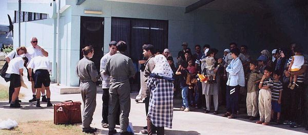 This file photo taken on August 19, 2001 shows officials (C-in green flight uniforms) questioning a refugee as other refugees (R), mostly believed to be from Iraq, wait in the shade before boarding an Australian Air Force Hercules aircraft on the Australian island territory of Christmas Island in the Indian Ocean. This file photo taken on August 19, 2001 shows officials (C-in green flight uniforms) questioning a refugee as other refugees (R), mostly believed to be from Iraq, wait in the shade before boarding an Australian Air Force Hercules aircraft on the Australian island territory of Christmas Island in the Indian Ocean. - Sputnik International