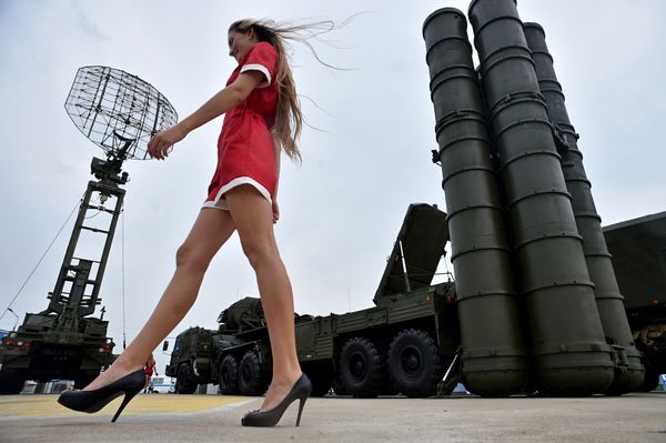 A woman walks near Russia's air defence system S-400 Triumf launch vehicles at the military exhibition - Sputnik International