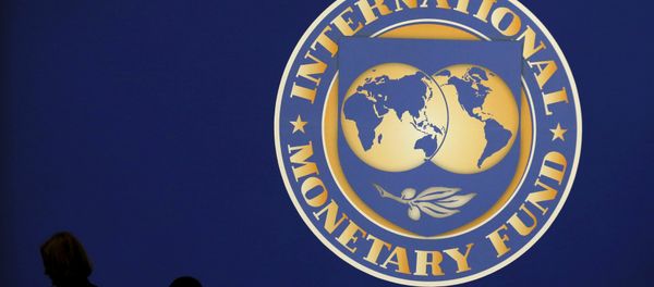 Visitors are silhouetted against the logo of the International Monetary Fund at the main venue for the IMF and World Bank annual meeting in Tokyo in this October 10, 2012 file photo. - Sputnik International