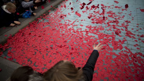 School pupils throw poppies into a fountain after observing a two minute silence to mark Armistice Day, in Trafalgar Square, London, Wednesday, Nov. 11, 2015. - Sputnik International