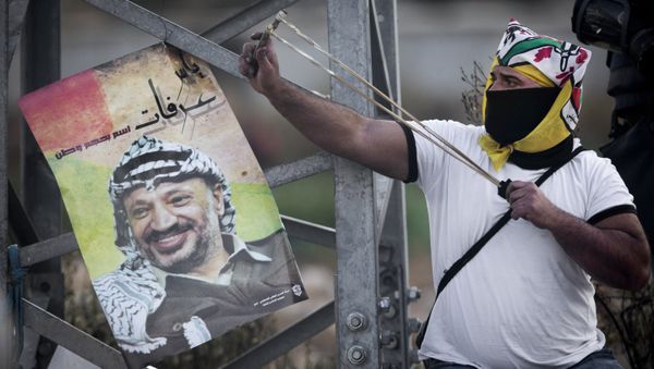 A Palestinian protester uses a slingshot to throw stones towards Israeli security forces during clashes following a protest to mark the 11th anniversary of the death of Palestinian leader Yasser Arafat, in the West Bank city of Ramallah, Wednesday, Nov. 11, 2015. - Sputnik International