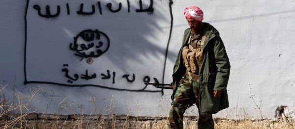 A Kurdish fighter walks by a wall bearing a drawing of the flag of the Islamic State (IS) group in the northern Iraqi town of Sinjar, in the Nineveh Province, on November 13, 2015. Iraqi Kurdish leader Massud Barzani announced the liberation of Sinjar from the Islamic State group in an assault backed by US-led strikes that cut a key jihadist supply line with Syria. - Sputnik International