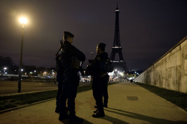Police officers stand guard near the Eiffel Tower which has its lights turned off on November 14, 2015 following the deadly attacks in Paris.   - Sputnik International