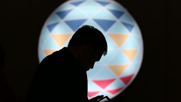 FILE - In this Sunday, Nov. 15, 2015, file photo, a Filipino checks his smartphone in front of the logo of APEC 2015 in Manila, Philippines FILE - In this Sunday, Nov. 15, 2015, file photo, a Filipino checks his smartphone in front of the logo of APEC 2015 in Manila, Philippines - Sputnik International