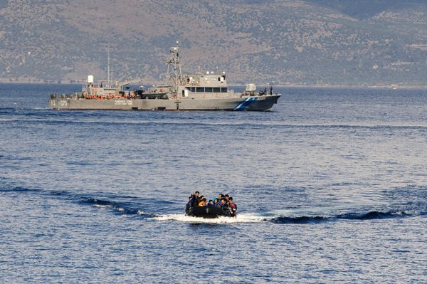 A Greek coast guard ship is seen behind a rubber boat with refugees and migrants near the Greek island of Lesbos after crossing the Aegean Sea from Turkey on October 13, 2015. - Sputnik International