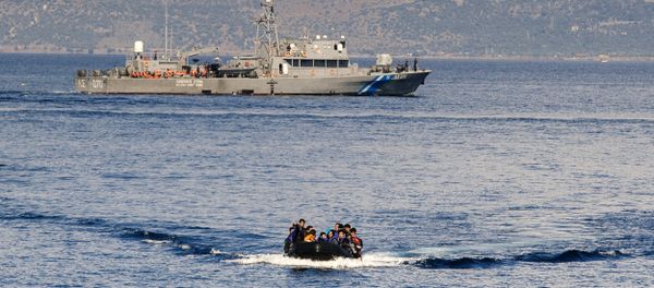 A Greek coast guard ship is seen behind a rubber boat with refugees and migrants near the Greek island of Lesbos after crossing the Aegean Sea from Turkey on October 13, 2015 A Greek coast guard ship is seen behind a rubber boat with refugees and migrants near the Greek island of Lesbos after crossing the Aegean Sea from Turkey on October 13, 2015 - Sputnik International