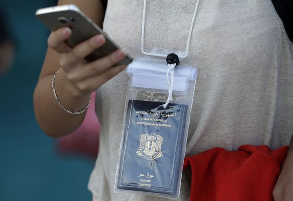 A Syrian woman uses her cell phone as she carries in a waterproof bag her passport after her arrival on a ferry from the Greek island of Lesbos at the Athens' port of Piraeus A Syrian woman uses her cell phone as she carries in a waterproof bag her passport after her arrival on a ferry from the Greek island of Lesbos at the Athens' port of Piraeus - Sputnik International