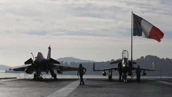 Flight deck crew work around a Rafale (L) and a Super Etendard fighter jets as a French flag flies aboard the French nuclear-powered aircraft carrier Charles de Gaulle before its departure from the naval base of Toulon, France, November 18, 2015 Flight deck crew work around a Rafale (L) and a Super Etendard fighter jets as a French flag flies aboard the French nuclear-powered aircraft carrier Charles de Gaulle before its departure from the naval base of Toulon, France, November 18, 2015 - Sputnik International