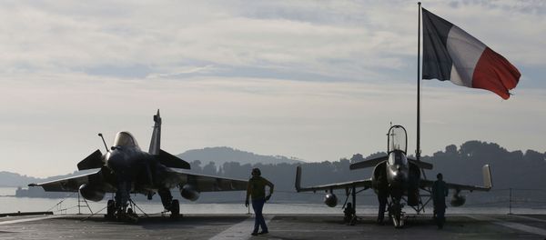 Flight deck crew work around a Rafale (L) and a Super Etendard fighter jets as a French flag flies aboard the French nuclear-powered aircraft carrier Charles de Gaulle before its departure from the naval base of Toulon, France, November 18, 2015 Flight deck crew work around a Rafale (L) and a Super Etendard fighter jets as a French flag flies aboard the French nuclear-powered aircraft carrier Charles de Gaulle before its departure from the naval base of Toulon, France, November 18, 2015 - Sputnik International