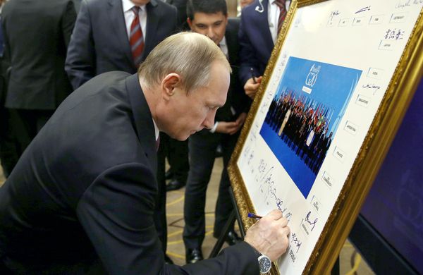 Russian President Vladimir Putin signs a print of the G20-Turkey family photo at the Group of 20 (G20) summit, in the Mediterranean resort city of Antalya, on November 15, 2015 Russian President Vladimir Putin signs a print of the G20-Turkey family photo at the Group of 20 (G20) summit, in the Mediterranean resort city of Antalya, on November 15, 2015 - Sputnik International