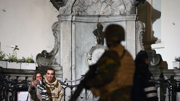A soldier patrols around a security perimeter next to tourists taking a photo of the Manneken Pis statue, as a reported police intervention takes place, in Brussels on November 22, 2015. A soldier patrols around a security perimeter next to tourists taking a photo of the Manneken Pis statue, as a reported police intervention takes place, in Brussels on November 22, 2015. - Sputnik International