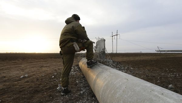 A man steps on a damaged electrical pylon near the village of Chaplynka in Kherson region, Ukraine, November 22, 2015 - Sputnik International