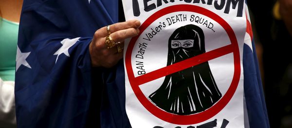 A supporter of the anti-Islam group Reclaim Australia with an Australian national flag drapped around him, holds a placard during a rally in central Sydney, Australia, November 22, 2015 - Sputnik International