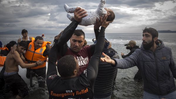 A volunteer holds up a baby as others help migrants and refugees to disembark from a dinghy after their arrival from the Turkish coast to the Greek island of Lesbos, Wednesday, Nov. 25, 2015. - Sputnik International