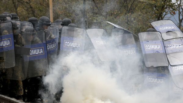 Macedonian police officers try to take cover from tear gas thrown back by a stranded migrant, as minor clashes broke out during a protest against the building of a metal fence at the Greek-Macedonian borders near the village of Idomeni, Greece November 28, 2015 Macedonian police officers try to take cover from tear gas thrown back by a stranded migrant, as minor clashes broke out during a protest against the building of a metal fence at the Greek-Macedonian borders near the village of Idomeni, Greece November 28, 2015 - Sputnik International