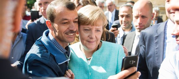 Asylum seeker (C, L) takes a selfie picture with German Chancellor Angela Merkel (C, R) following Merkel's visit at a branch of the Federal Office for Migration and Refugees and a camp for asylum-seekers in Berlin on September 10, 2015 - Sputnik International