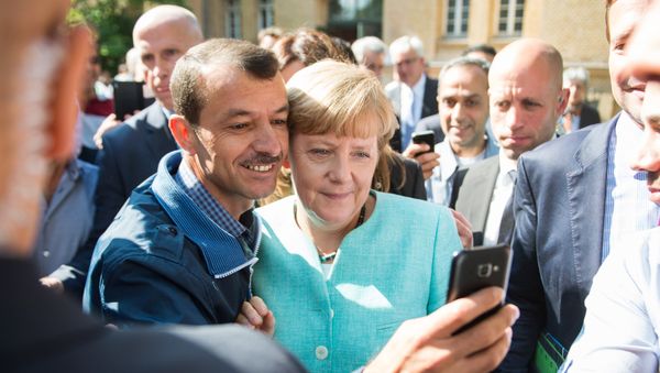 Asylum seeker (C, L) takes a selfie picture with German Chancellor Angela Merkel (C, R) following Merkel's visit at a branch of the Federal Office for Migration and Refugees and a camp for asylum-seekers in Berlin on September 10, 2015 Asylum seeker (C, L) takes a selfie picture with German Chancellor Angela Merkel (C, R) following Merkel's visit at a branch of the Federal Office for Migration and Refugees and a camp for asylum-seekers in Berlin on September 10, 2015 - Sputnik International