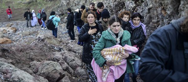 A woman carries a baby as people walk on shore after arriving with other migrants and refugees on the Greek island of Lesbos by crossing the Aegean Sea from Turkey on November 26, 2015 A woman carries a baby as people walk on shore after arriving with other migrants and refugees on the Greek island of Lesbos by crossing the Aegean Sea from Turkey on November 26, 2015 - Sputnik International