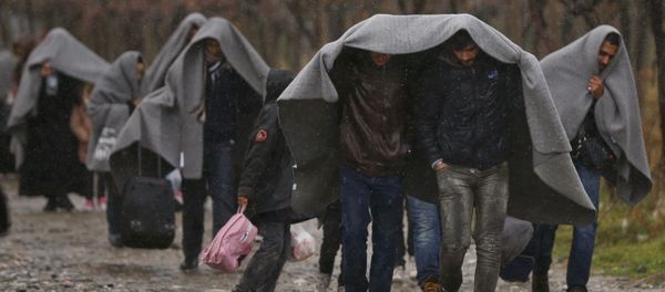 Migrants shield from rain with blankets as they walk after crossing the border from Greece into Macedonia, near Gevgelija, Macedonia, November 27, 2015 - Sputnik International