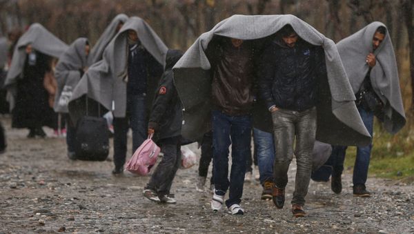 Migrants shield from rain with blankets as they walk after crossing the border from Greece into Macedonia, near Gevgelija, Macedonia, November 27, 2015 Migrants shield from rain with blankets as they walk after crossing the border from Greece into Macedonia, near Gevgelija, Macedonia, November 27, 2015 - Sputnik International