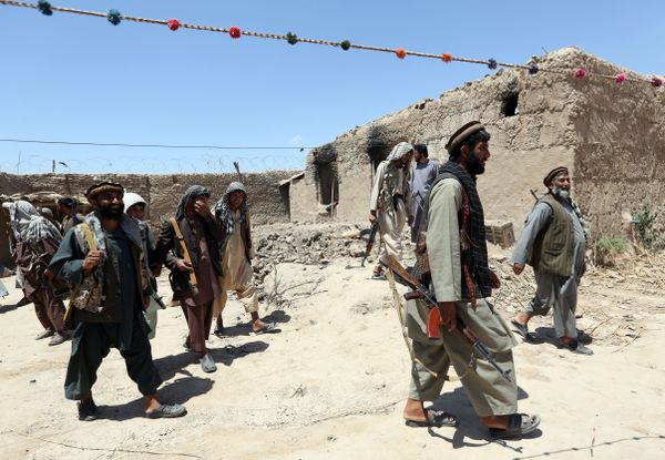 In this Thursday, May 21, 2015 file photo, local militia group fighters walk past a building torched by Taliban fighters at Talawka village in Kunduz province, north of Kabul, Afghanistan - Sputnik International