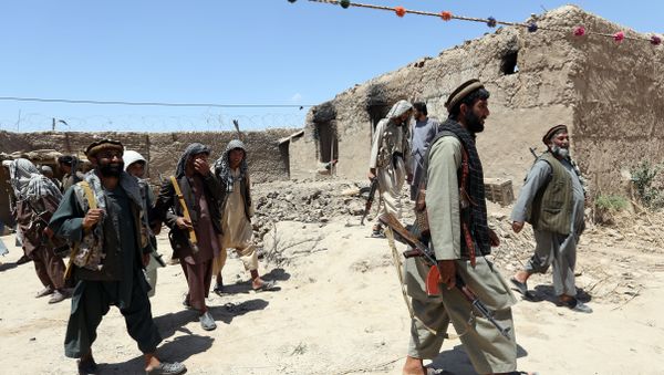 In this Thursday, May 21, 2015 file photo, local militia group fighters walk past a building torched by Taliban fighters at Talawka village in Kunduz province, north of Kabul, Afghanistan - Sputnik International