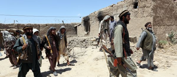 In this Thursday, May 21, 2015 file photo, local militia group fighters walk past a building torched by Taliban fighters at Talawka village in Kunduz province, north of Kabul, Afghanistan In this Thursday, May 21, 2015 file photo, local militia group fighters walk past a building torched by Taliban fighters at Talawka village in Kunduz province, north of Kabul, Afghanistan - Sputnik International