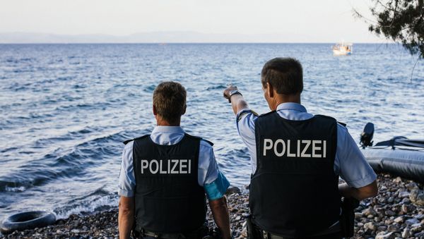 German police officers, representatives of the EU's border management agency Frontex, on the Greek island of Lesbos, look at a dinghy with migrants crossing the Aegean sea from Turkey, on October 17, 2015. - Sputnik International