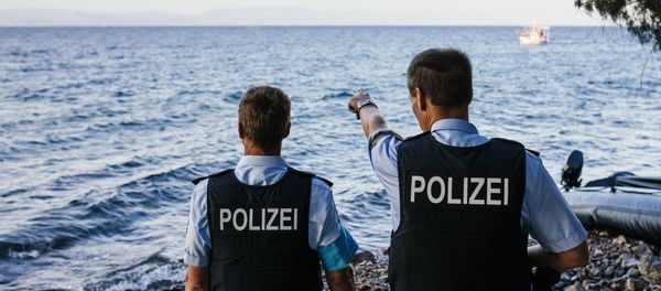 German police officers, representatives of the EU's border management agency Frontex, on the Greek island of Lesbos, look at a dinghy with migrants crossing the Aegean sea from Turkey, on October 17, 2015. German police officers, representatives of the EU's border management agency Frontex, on the Greek island of Lesbos, look at a dinghy with migrants crossing the Aegean sea from Turkey, on October 17, 2015. - Sputnik International