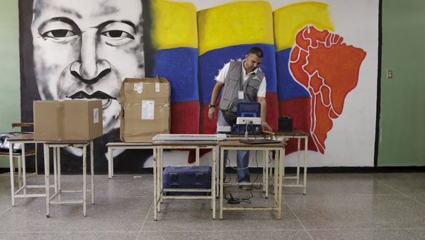 A worker of the National Electoral Council (CNE) configures a voting machine in front of a mural depicting Venezuela's late President Hugo Chavez at a school in Caracas, December 4, 2015. Venezuela will hold parliamentary elections on December 6. A worker of the National Electoral Council (CNE) configures a voting machine in front of a mural depicting Venezuela's late President Hugo Chavez at a school in Caracas, December 4, 2015. Venezuela will hold parliamentary elections on December 6. - Sputnik International