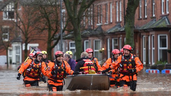 Members of the emergency services carry people to safety from a flooded street in Carlisle on December 6, 2015. One man was killed yesterday as Storm Desmond whipped across Britain, bringing heavy rain, strong winds and flooding to parts of the country. - Sputnik International