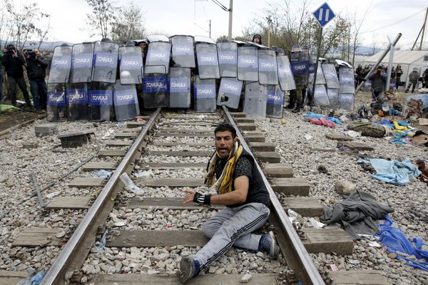A stranded migrant reacts in front of a Macedonian police cordon as they clash after a migrant was injured when he climbed on top of a train wagon, near the village of Idomeni, Greece, November 28, 2015. A stranded migrant reacts in front of a Macedonian police cordon as they clash after a migrant was injured when he climbed on top of a train wagon, near the village of Idomeni, Greece, November 28, 2015. - Sputnik International