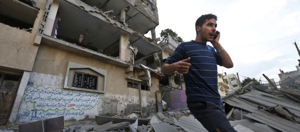 Palestinian talks on a mobile phone as he walks on the rubble of a damaged house following an overnight Israeli missile strike in Gaza City, Tuesday, July 15, 2014 Palestinian talks on a mobile phone as he walks on the rubble of a damaged house following an overnight Israeli missile strike in Gaza City, Tuesday, July 15, 2014 - Sputnik International