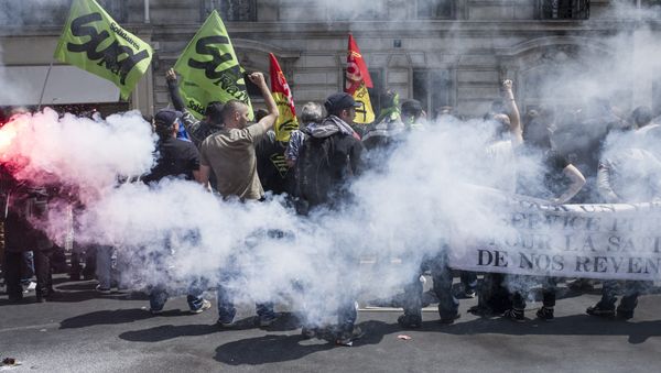 Striking workers of the French state-run rail operator SNCF, backed by French unions CGT and Sud-Rail, protest with flares during a demonstration against reform plans proposed by the French government, on June 18, 2014, at the Austerlitz train station in Paris - Sputnik International