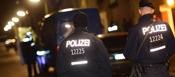 Armed police stand guard as others search a van at the scene in the Karl-Elsasser Street in Berlin's southern suburb of Britz on November 26, 2015. German police detained two suspects in a series of raids targeting Islamists in Berlin and said they were examining a suspicious object - Sputnik International