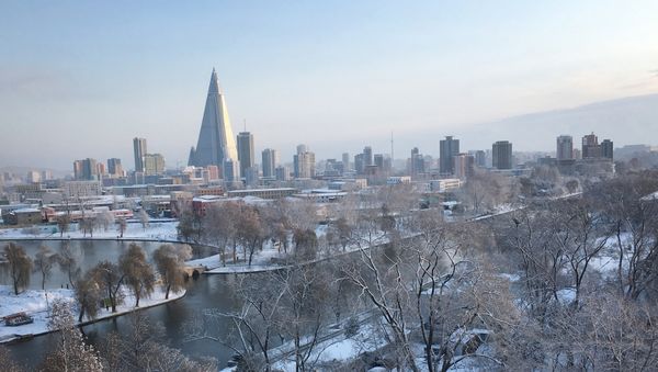 The 105-story pyramid-shaped Ryugyong Hotel towers over residential apartments and snow covered trees and fields on Thursday Dec. 3, 2015, in Pyongyang, North Korea where the winter season has started - Sputnik International
