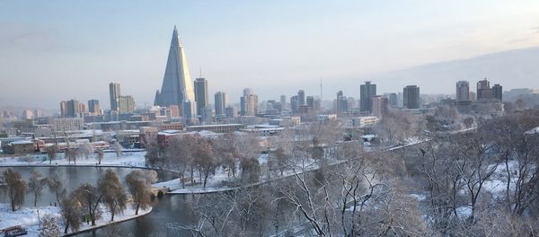 The 105-story pyramid-shaped Ryugyong Hotel towers over residential apartments and snow covered trees and fields on Thursday Dec. 3, 2015, in Pyongyang, North Korea where the winter season has started - Sputnik International