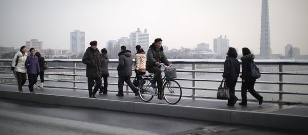 North Koreans walk along a bridge that takes them over the Taedong River on Wednesday, Dec. 2, 2015, in Pyongyang, North Korea. Seen in the background is the Juche Tower - Sputnik International