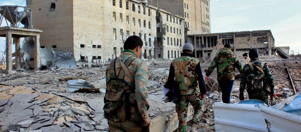 Syrian army soldiers patrol near a building previously used for storing seeds in the countryside of Deir Hafer, a former bastion of Islamic State group, near the northern Syrian city of Aleppo on December 2, 2015 - Sputnik International