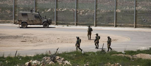 Israeli soldiers walk near a fence in the Israeli occupied Golan Heights on the border with war-torn Syria Israeli soldiers walk near a fence in the Israeli occupied Golan Heights on the border with war-torn Syria - Sputnik International