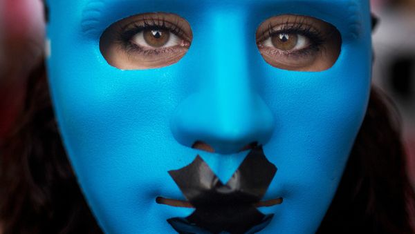 A protester wears a mask with a gag as she marches against the Public Security Law in Madrid, Spain, Tuesday, June 30, 2015. - Sputnik International