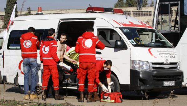 Members of the Syrian Red Crescent give aid to an injured man in the district of Waer in the central city of Homs on December 9, 2015 as hundreds of civilians and Syrian rebel forces began evacuating the last opposition-held district under a deal with the Syrian regime - Sputnik International