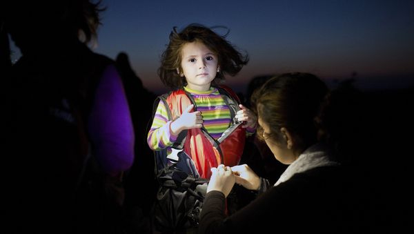 A child gets assistance to remove her life jacket upon her arrival on an inflatable boat carrying migrants on the Greek island of Kos after crossing a part of the Aegean Sea between Turkey and Greece on August 13, 2015. - Sputnik International