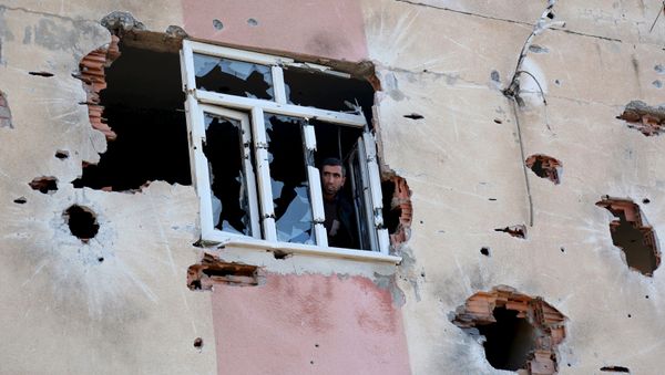 A man looks out of a building which was damaged during the security operations and clashes between Turkish security forces and Kurdish militants, in Sur district of Diyarbakir, Turkey - Sputnik International