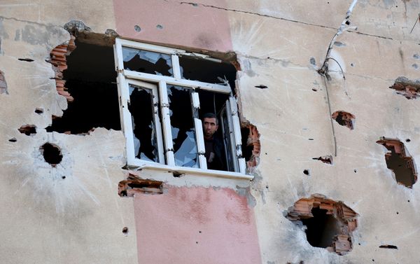 A man looks out of a building which was damaged during the security operations and clashes between Turkish security forces and Kurdish militants, in Sur district of Diyarbakir, Turkey - Sputnik International