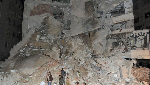 Members of Syrian security services and soldiers stand in front of a damaged building that was hit by an Israeli strike, killing a Lebanese militant leader Samir Qantar, in the Damascus district of Jaramana, Syria in this handout picture provided by SANA on December 20, 2015 - Sputnik International